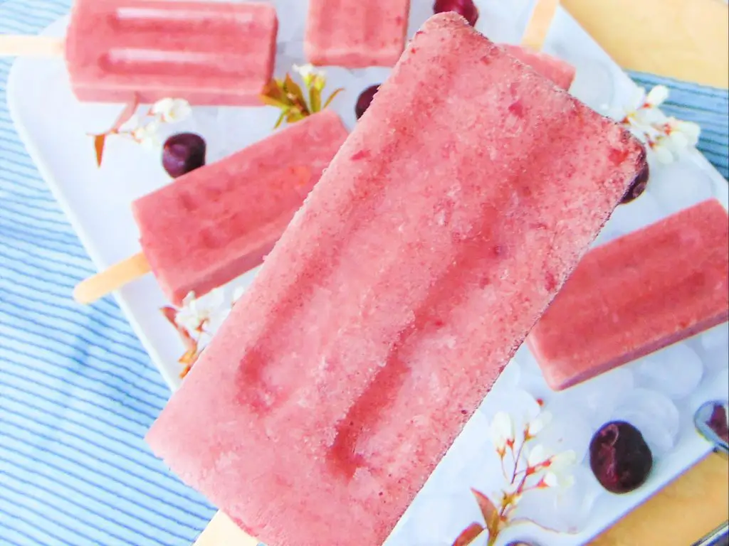 Cherry yogurt popsicle and more popsicles and cherries in the background