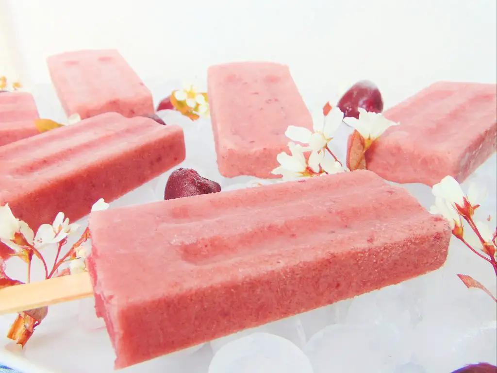 Cherry yogurt popsicles laying on ice