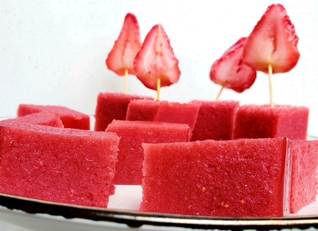 Cubes of strawberry gelatin and strawberry slices on a white plate