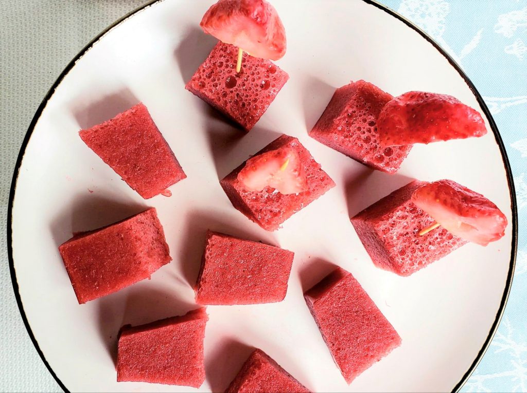 Strawberry gelatin cubes and strawberry slices on a white plate