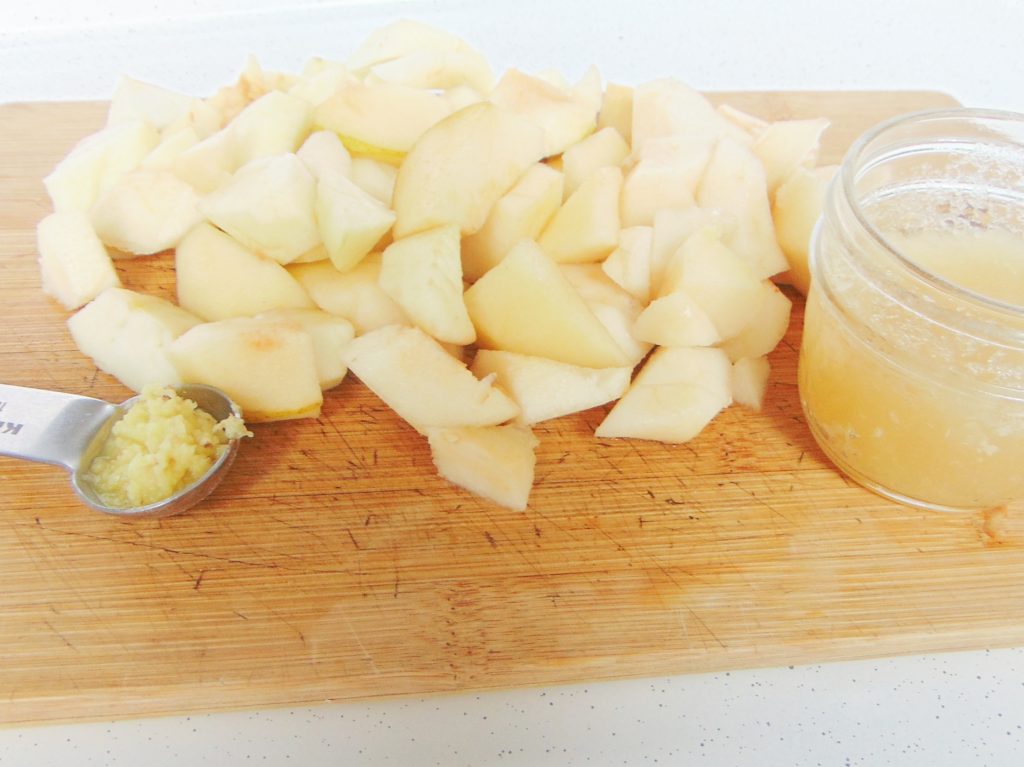Cubed pears, grated ginger and hydrated gelatin on a wooden cutting board