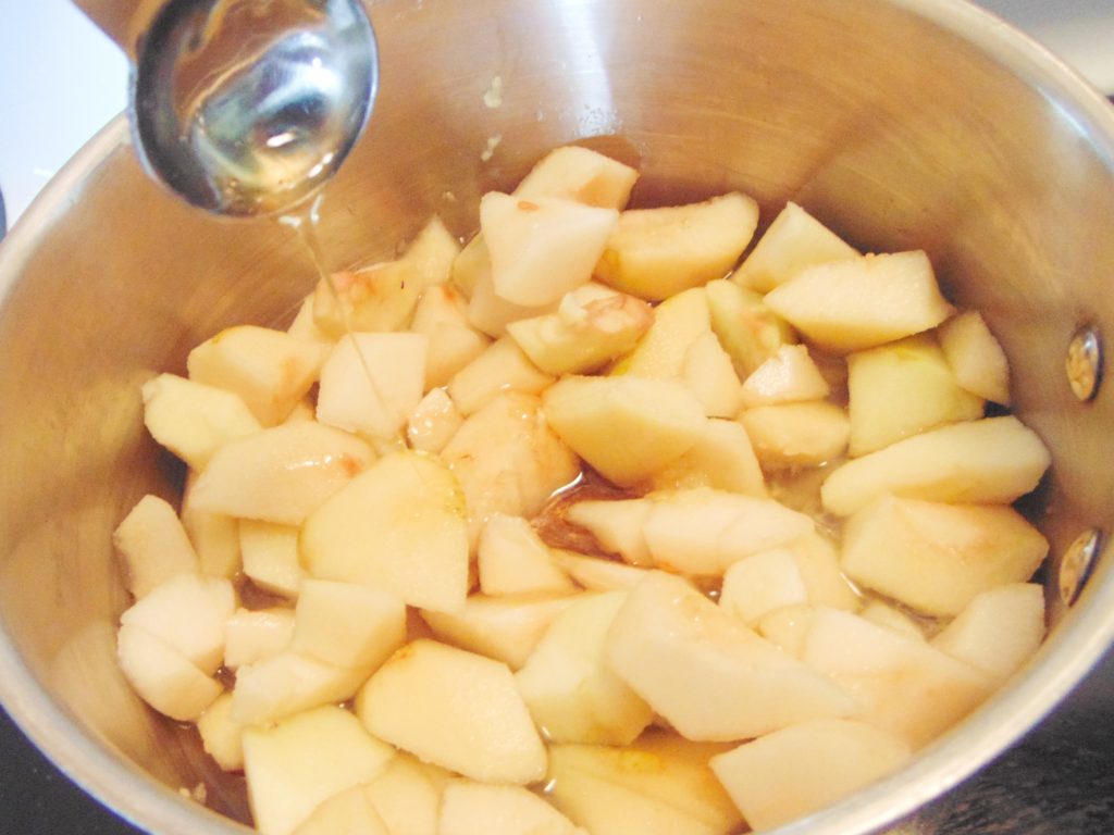 Cubed pears, grated ginger, water and honey cooking in a stainless steel saucepan