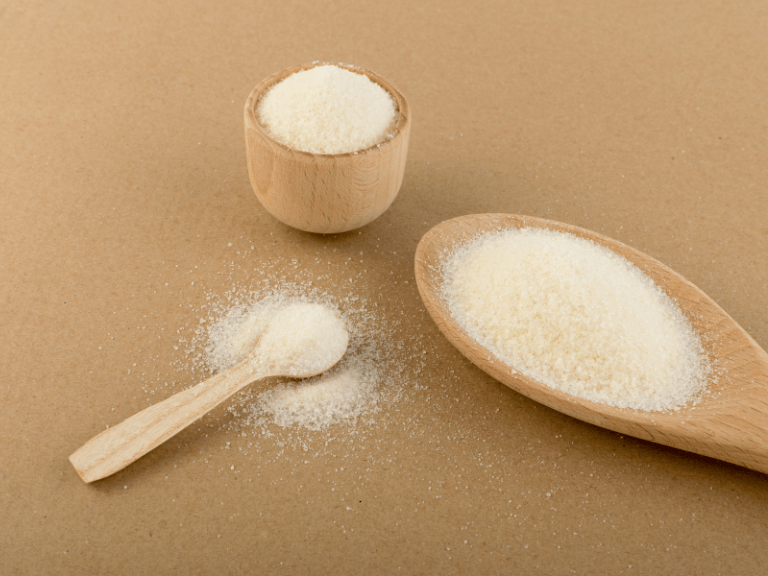 Collagen and gelatin powder on wooden spoons and brown background