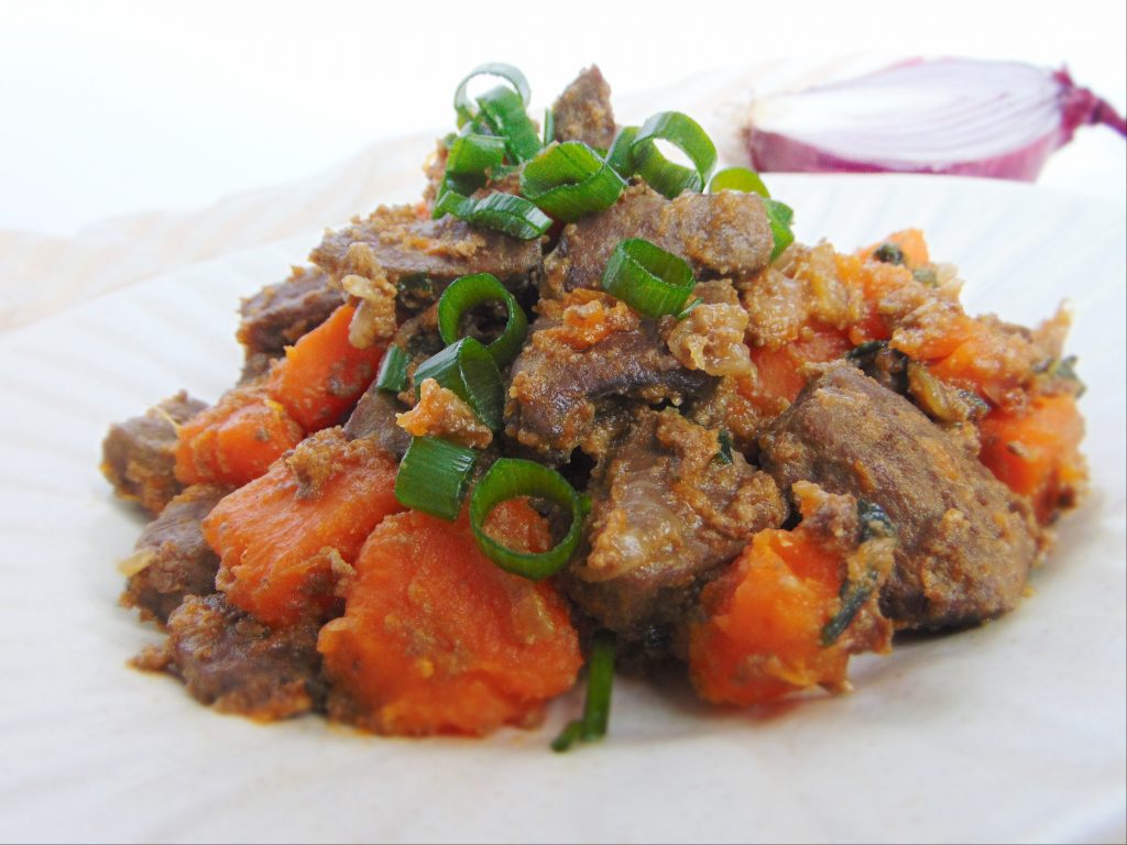Beef liver cooked with sweet potatoes and onions garnished with green onions served inn white plate