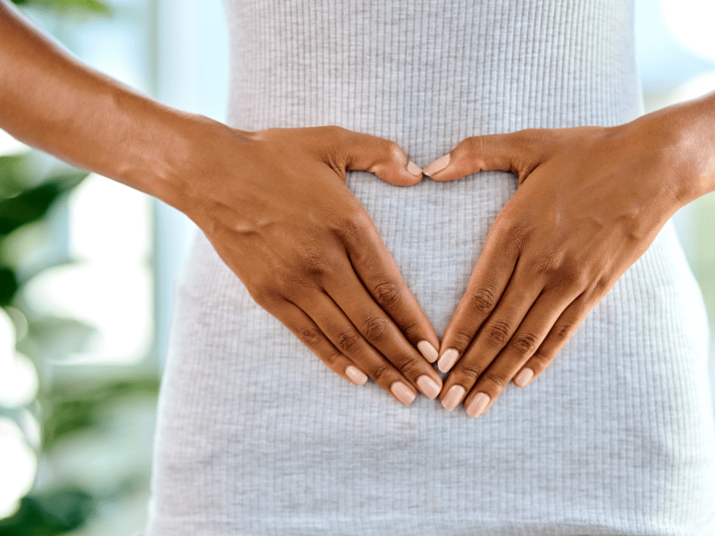 Woman's belly and heart shaped hands to symbolize gut health