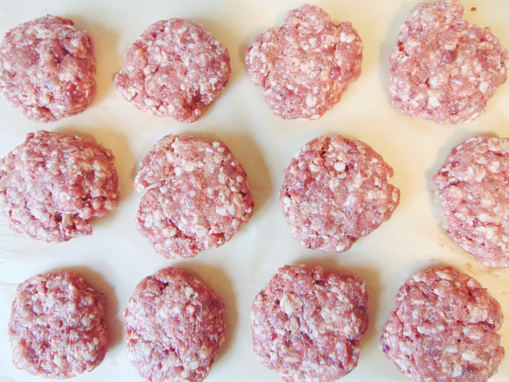 Uncooked organ meat sausage patties on parchment paper