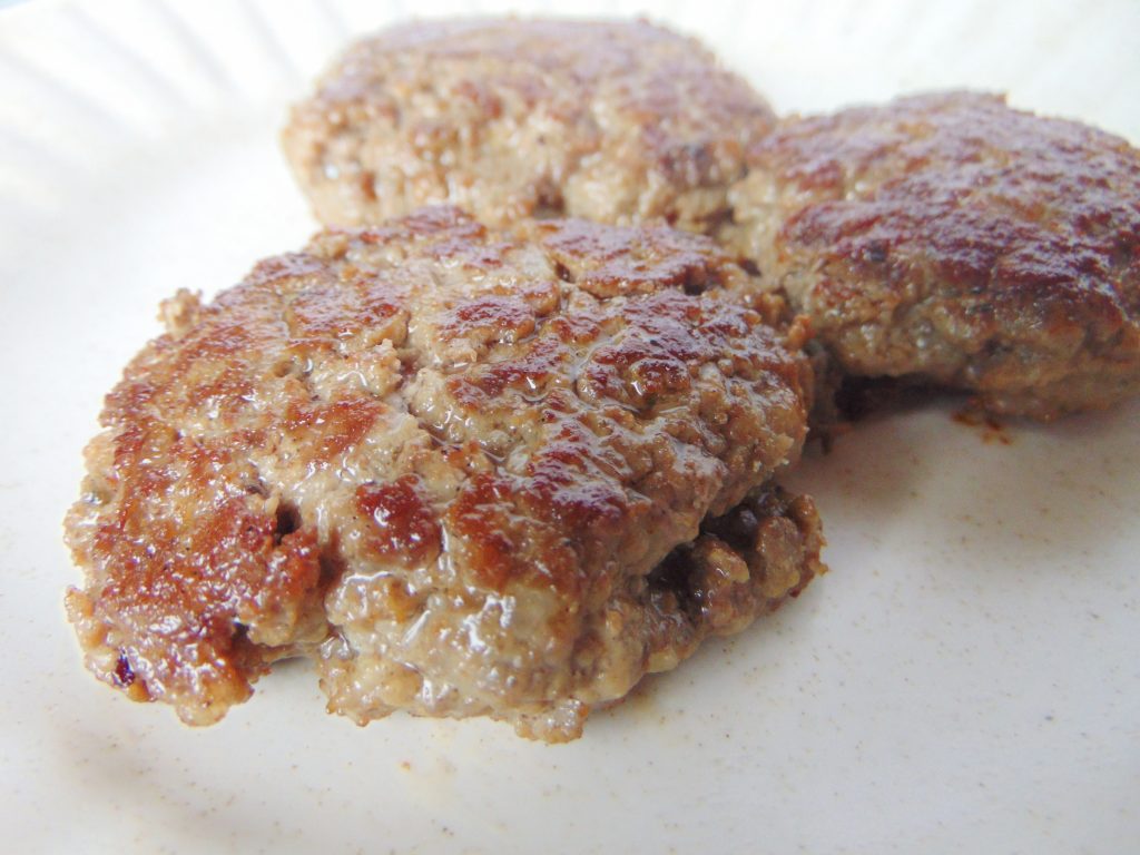 Cooked organ meat sausage patties on white plate