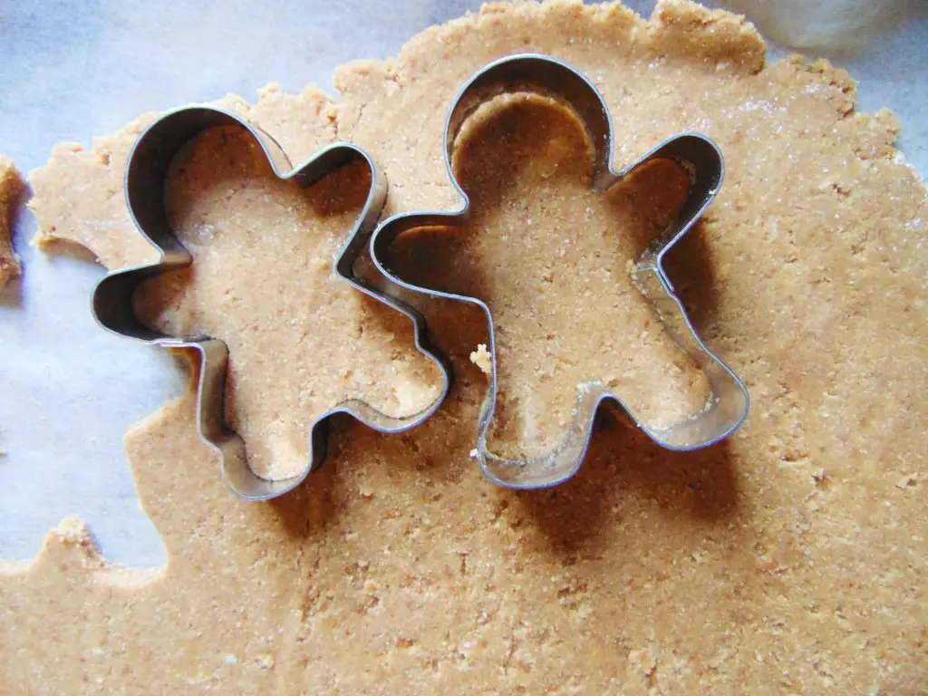 Cutting out coconut flour gingerbread man cookies with cookie cutters