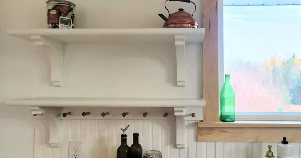White cottage style open kitchen shelves with corbels and shaker peg rails
