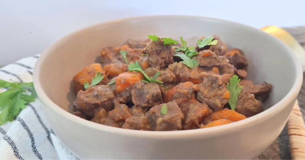 Bowl of heart and kidney stew with low carb veggies garnished with chopped parsley.