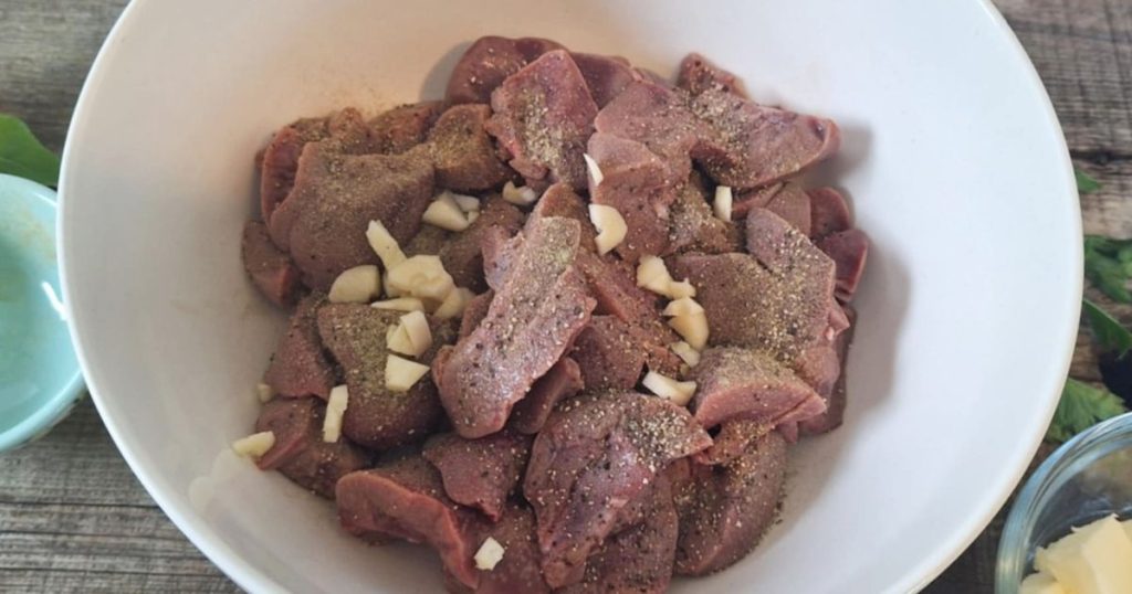 Pat dry beef kidney chunks tossed with seasoning in a white bowl getting ready to be pan-fried 